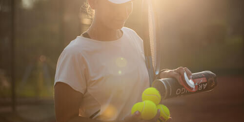 Une femme tient ses balles de tennis