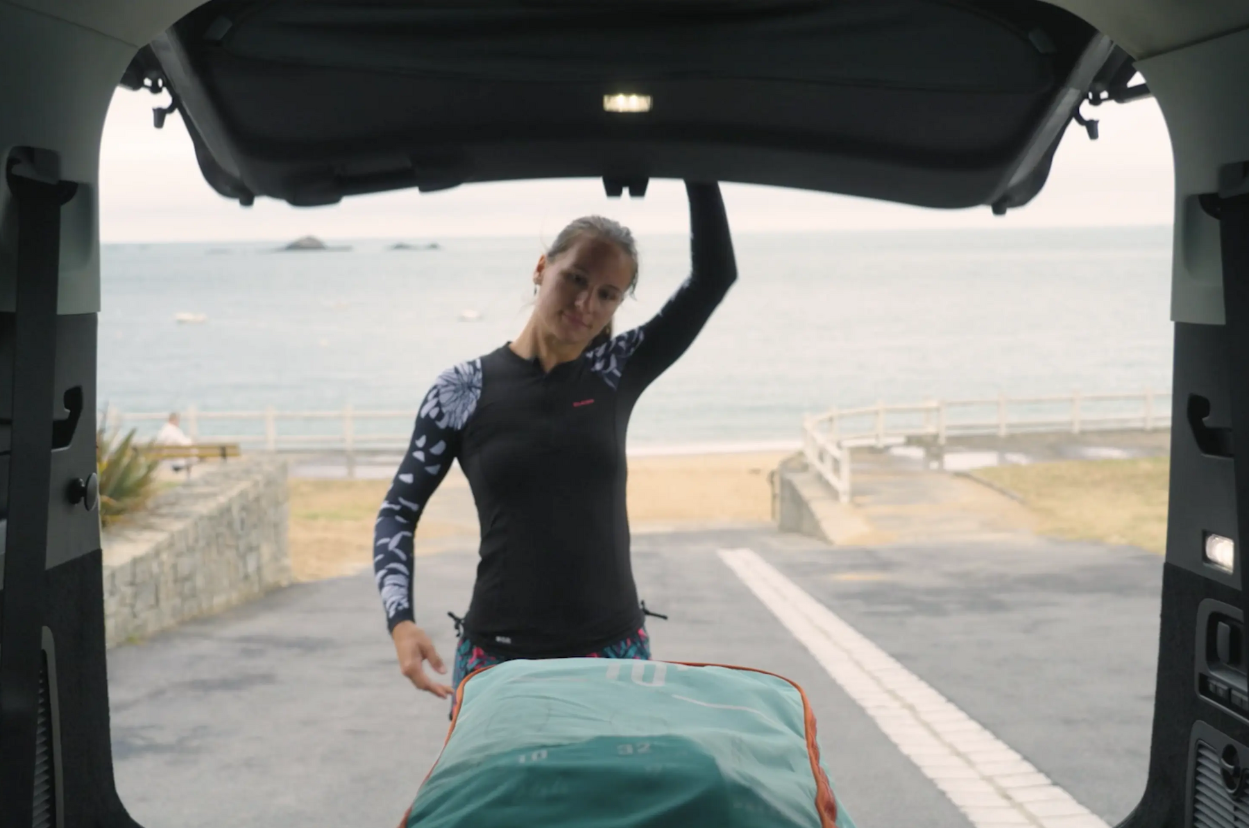 mujer transportando tabla paddle surf en el maletero