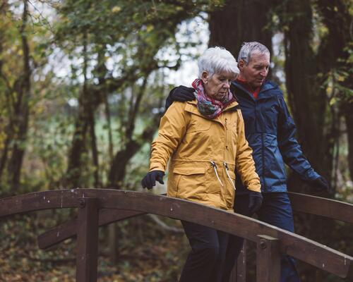 seniorzy w odzieży trekkingowej spacerujący w celu zapobiegania osteoporozie