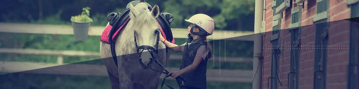 Girl petting her horse, wearing horse riding gear.