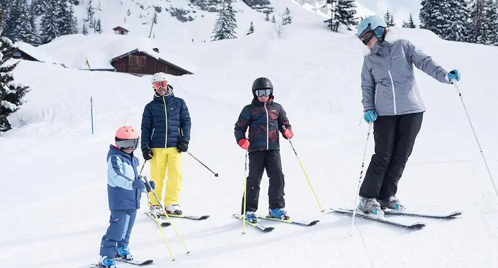 rodzina  ubrana w stroje narciarskie stojąca na stoku 