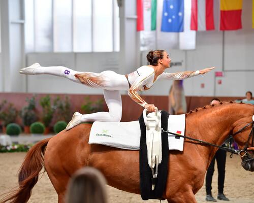kobieta w stroju gimnastycznym  wykonująca figurę na koniu