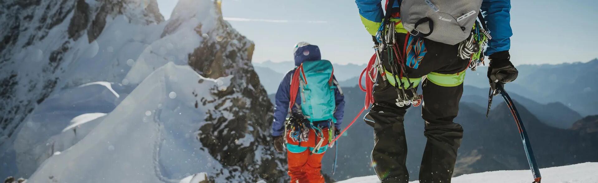 kobieta i mężczyzna wędrujący po górach w  strojach alpinistycznych z plecakami na plecach