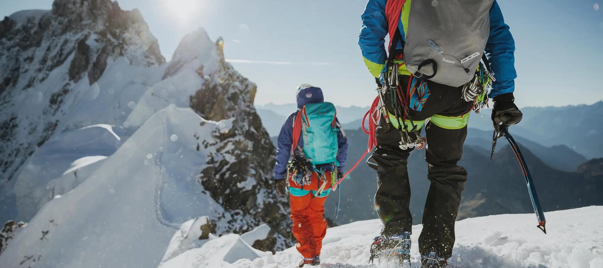 kobieta i mężczyzna wędrujący po górach w  strojach alpinistycznych z plecakami na plecach