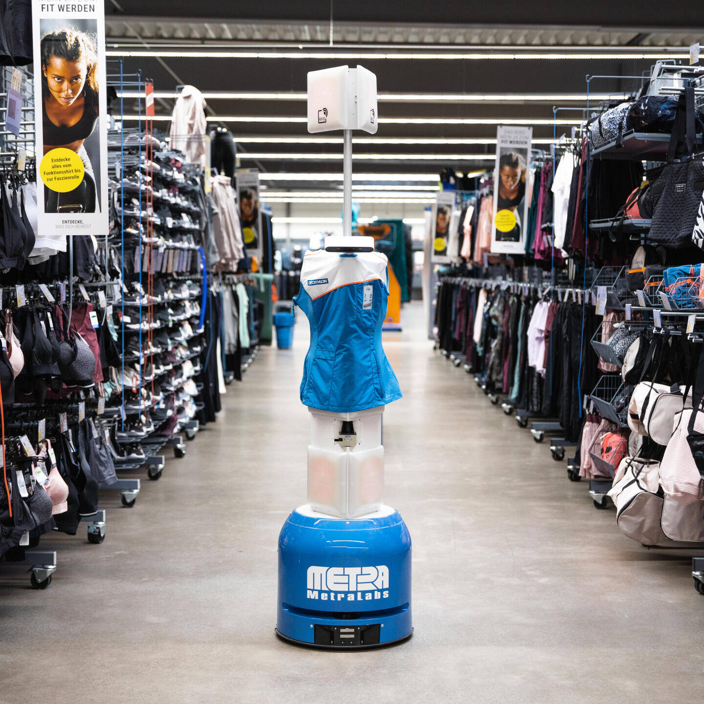 Der RFID Roboter steht mit der typischen DECATHLON-Weste im Gang einer Filiale