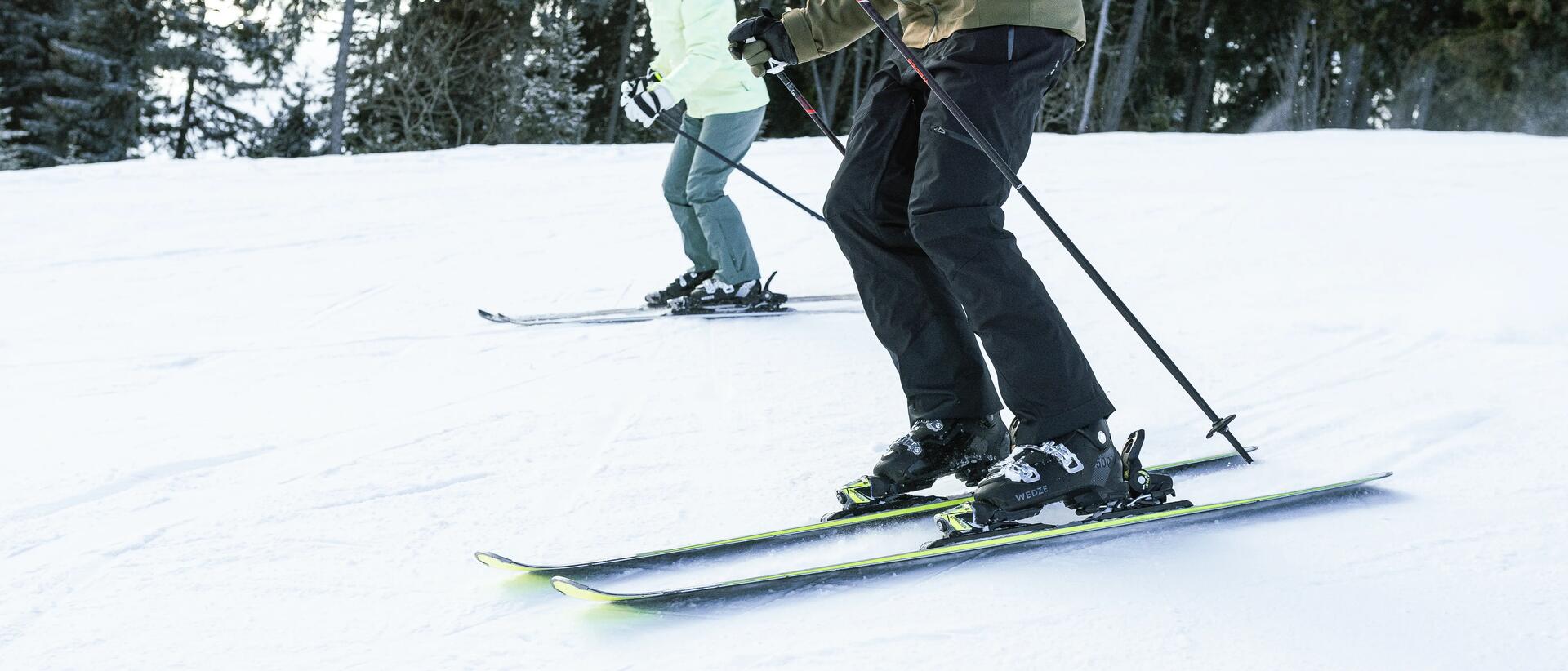 ludzie zjeżdżający na nartach z kijkami