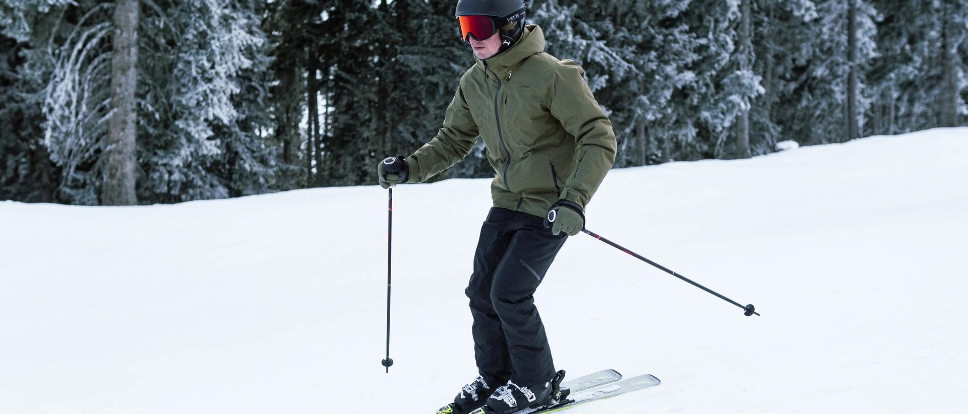 mężczyzna z kijkami w rękach zjeżdżający na nartach  ze stoku 