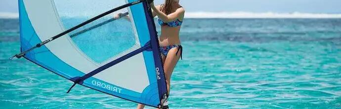 kobieta trzymająca za żagiel na desce windsurfingowej