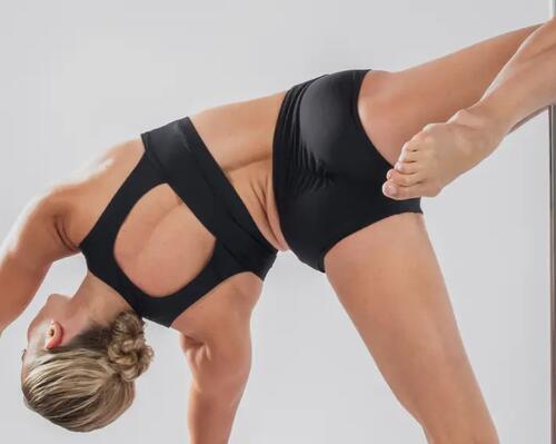 Kobieta w stroju do ćwiczeń wzmacniająca ręce i całe ciało podczas treningu pole dance