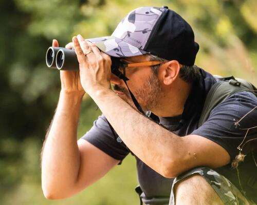 Man looking through binoculars from mountains