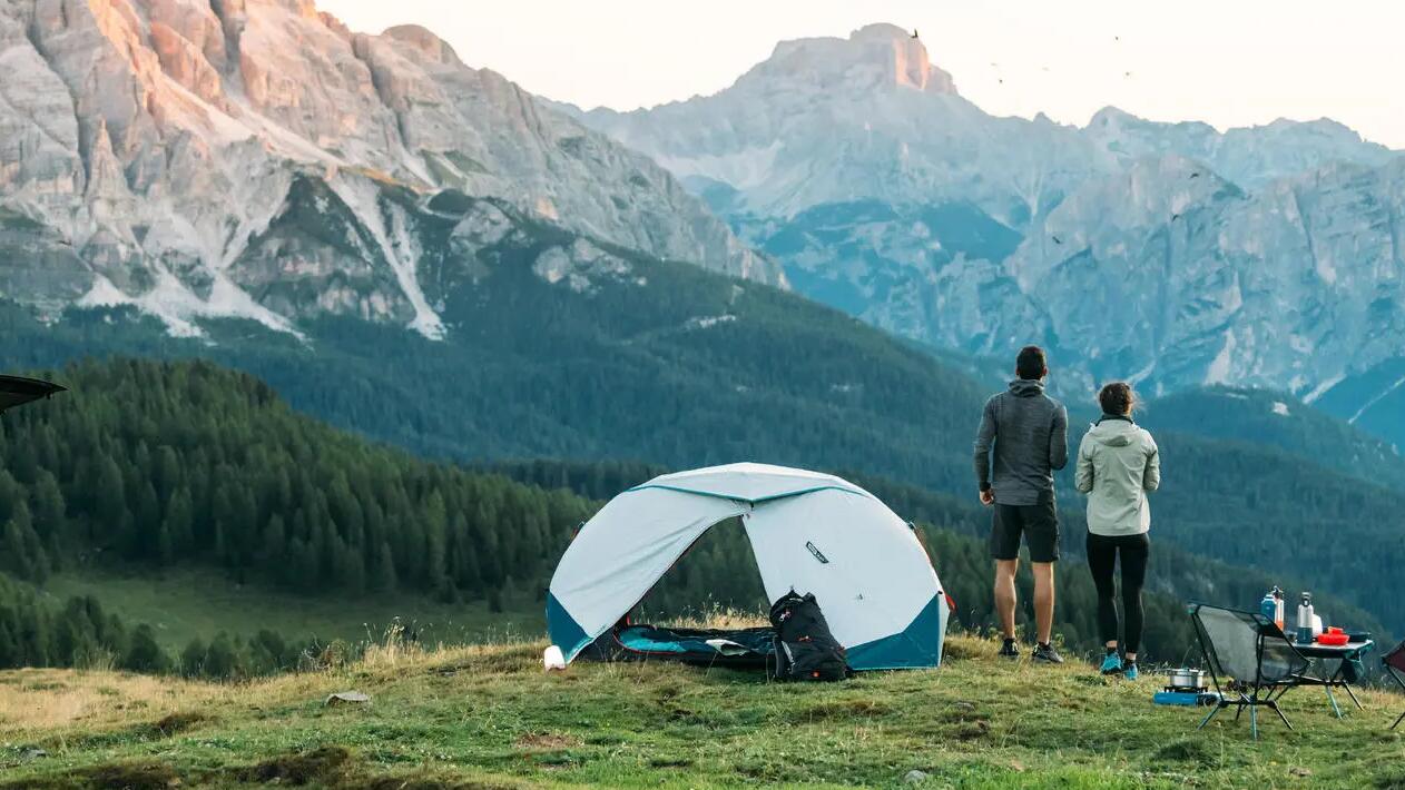 Man and woman looking at mountainous sights next to tent