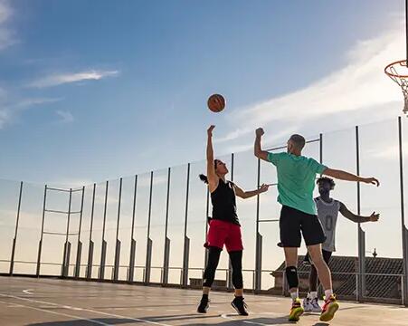 3 osoby grają w koszykówkę na boisku w odzieży sportowej