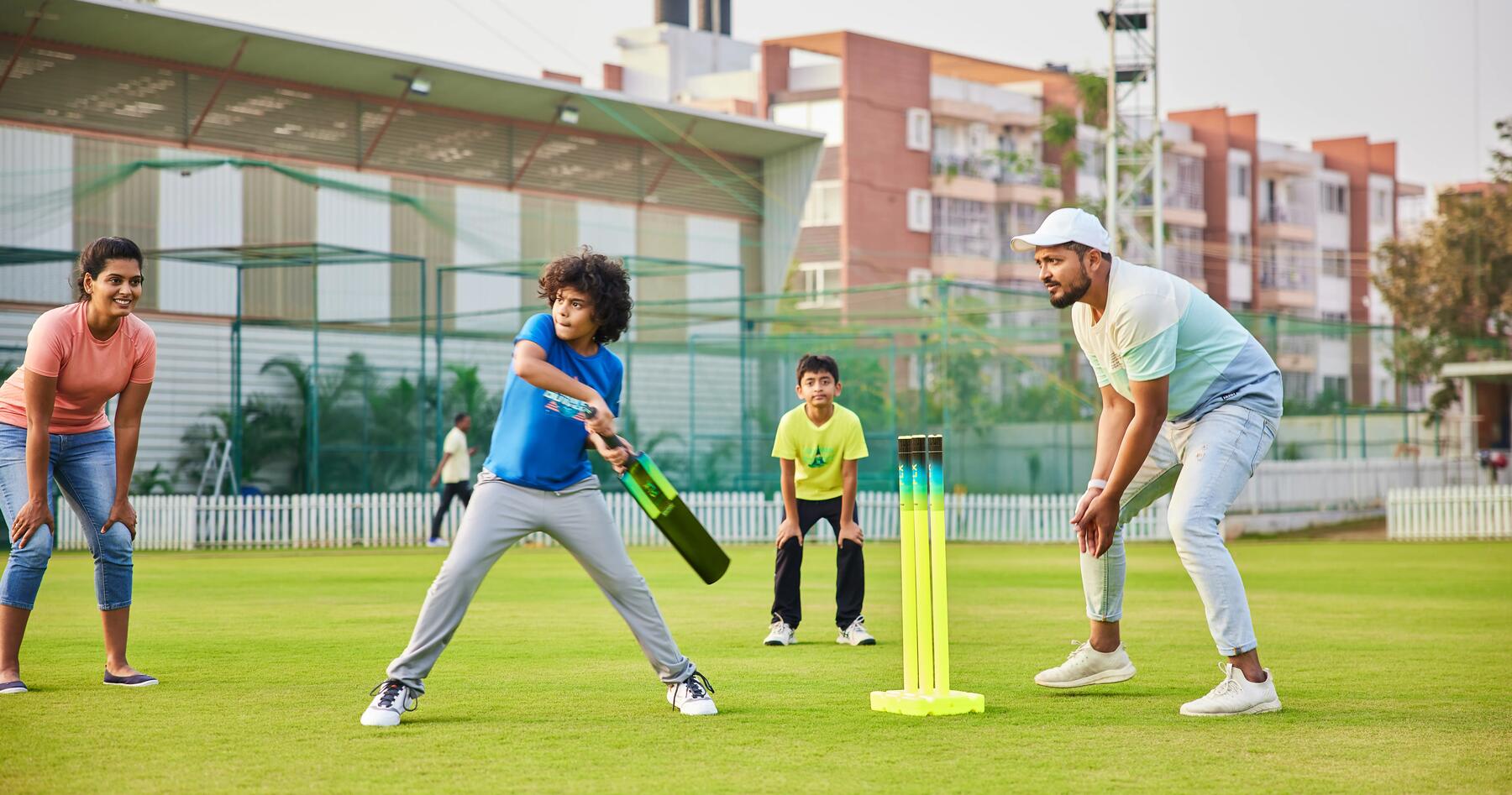 two kids and two adults playing cricket 