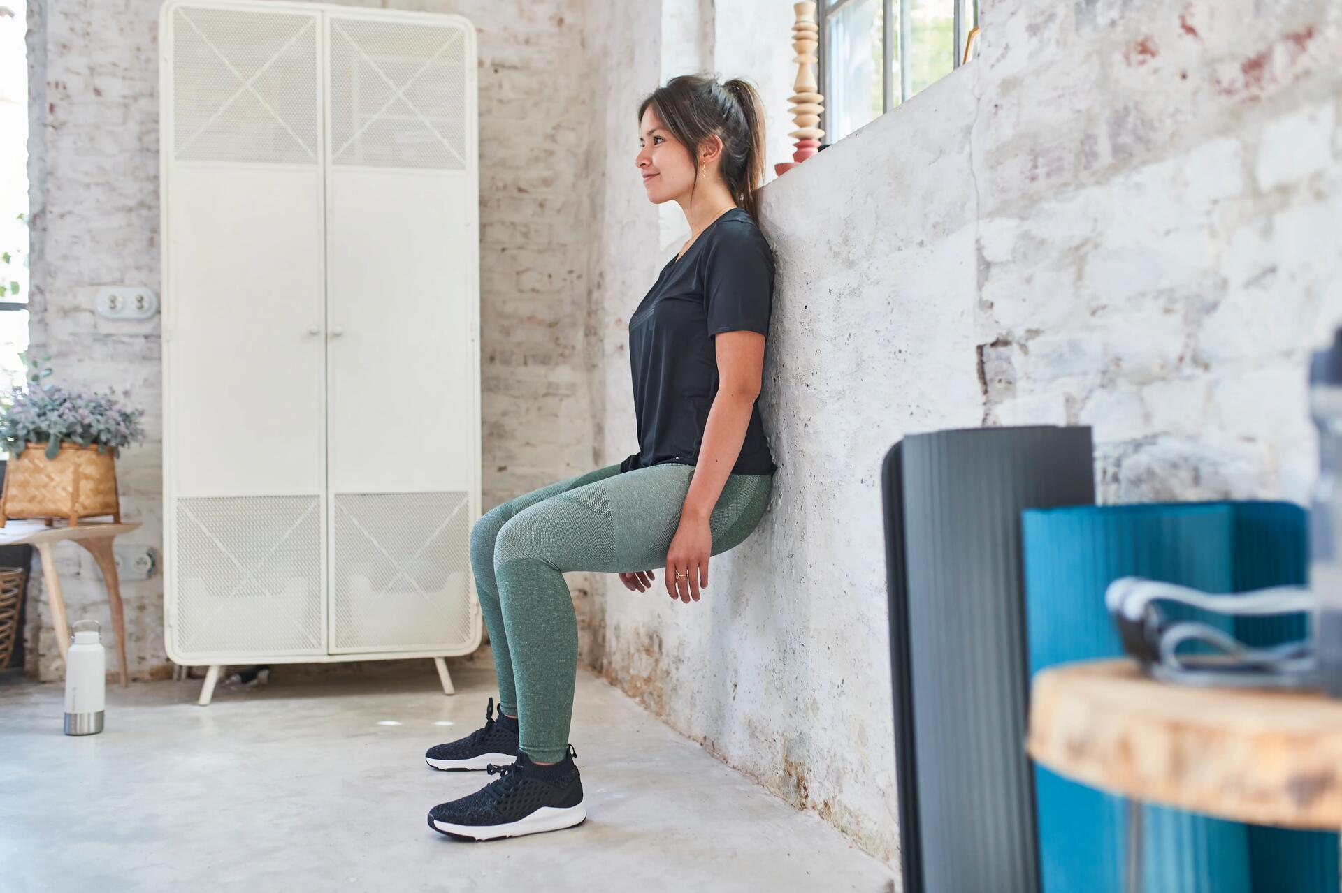 mujer haciendo ejercicio de la silla en pared