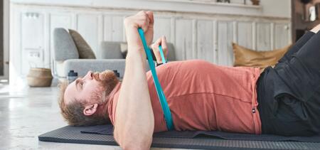 Homme qui fait un exercice sur le tapis avec un élastique