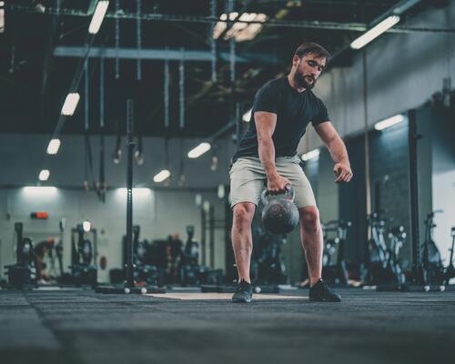 mężczyzna w odzieży fitness podnoszący kettlebell