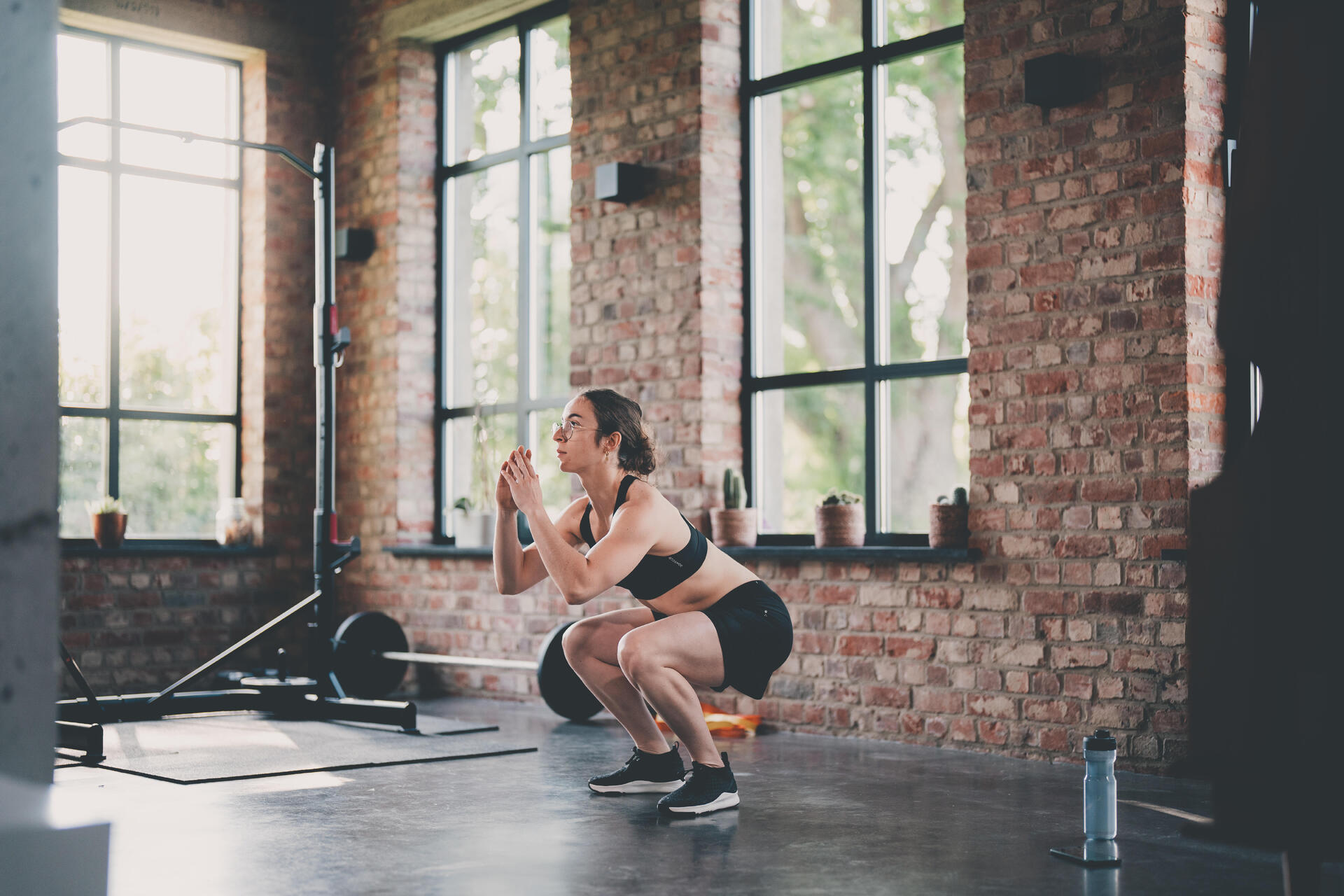 Kobieta w odzieży fitness wykonująca przysiady w domowej siłowni