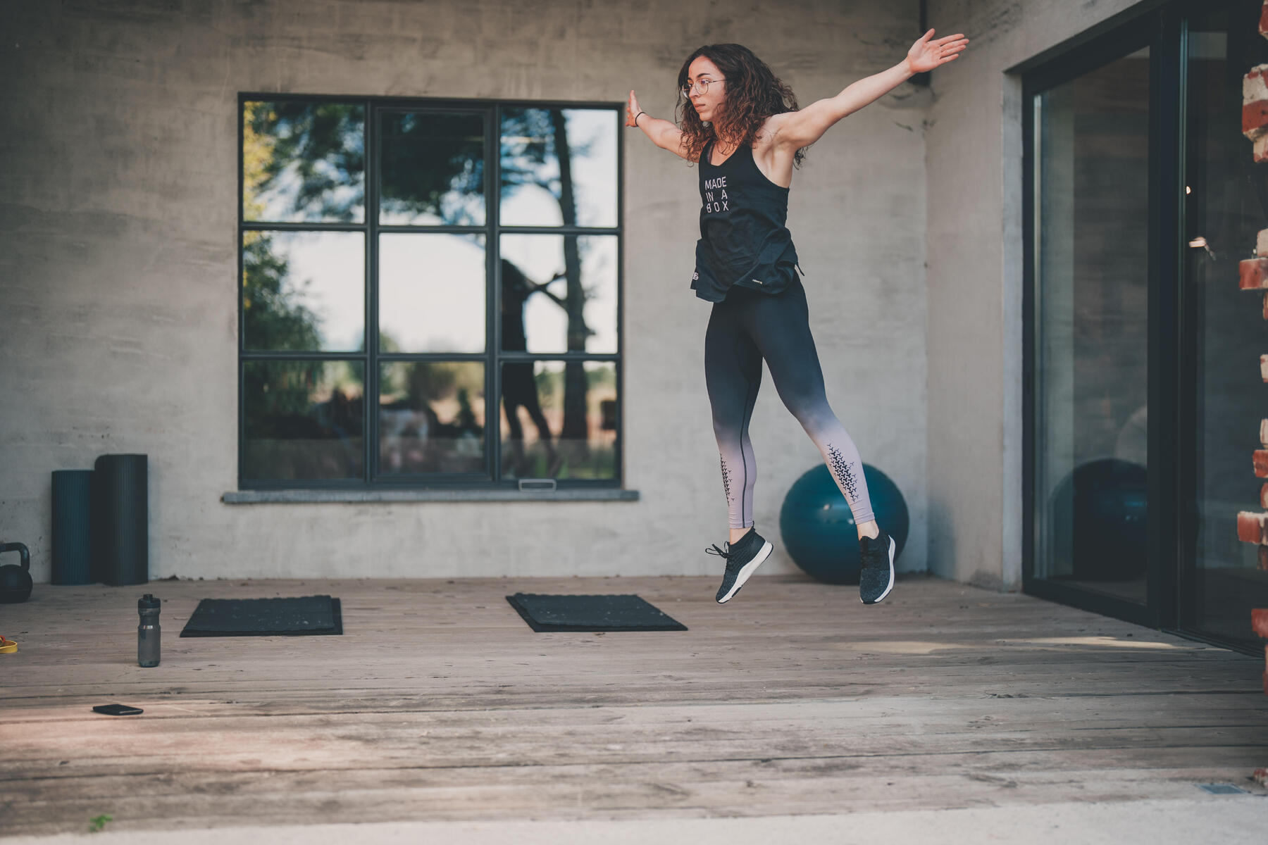 Eine Frau macht Cardio Training in Form von Burpees auf ihrer Veranda