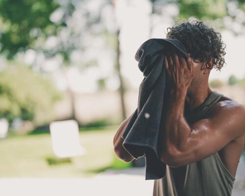 Man wipes his face with a towel after a workout