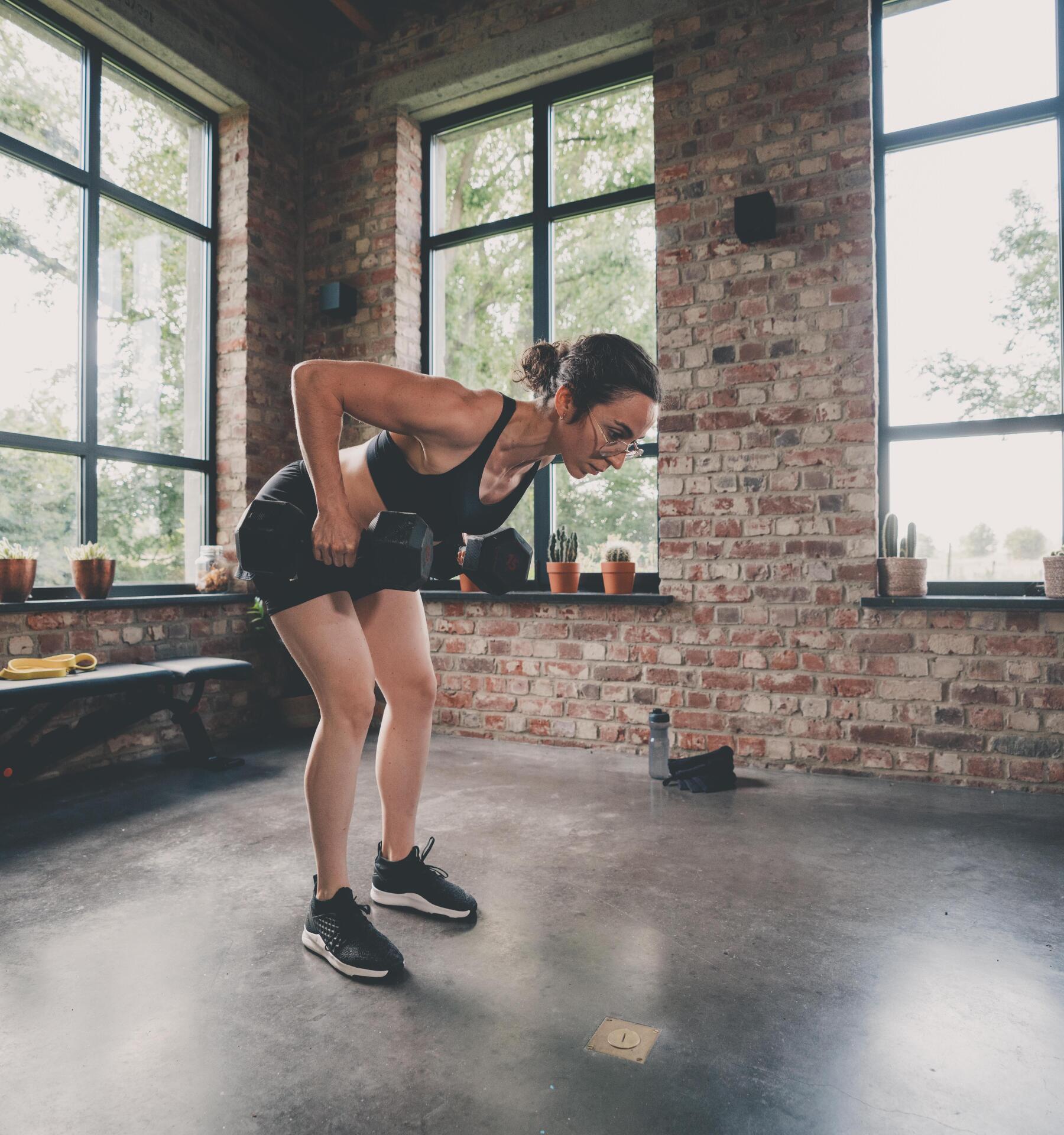 Femme Sportive Faisant De L'exercice Avec Deux Haltères à La