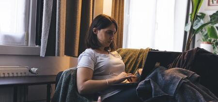 femme sur l'ordinateur allongée dans son canapé