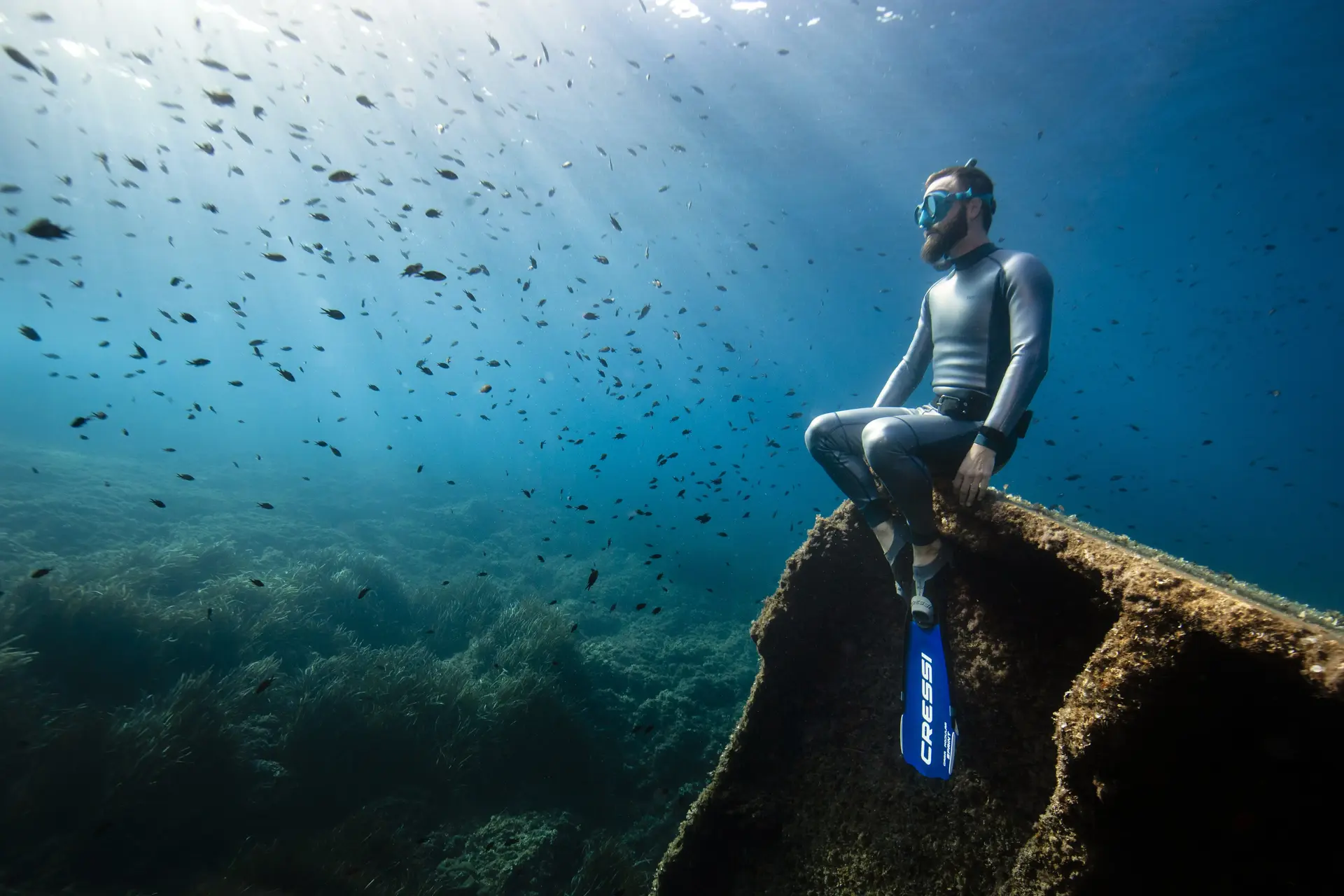 Mężczyzna uprawiający freediving siedzący na wraku statku pod wodą bijący rekord we freedivingu