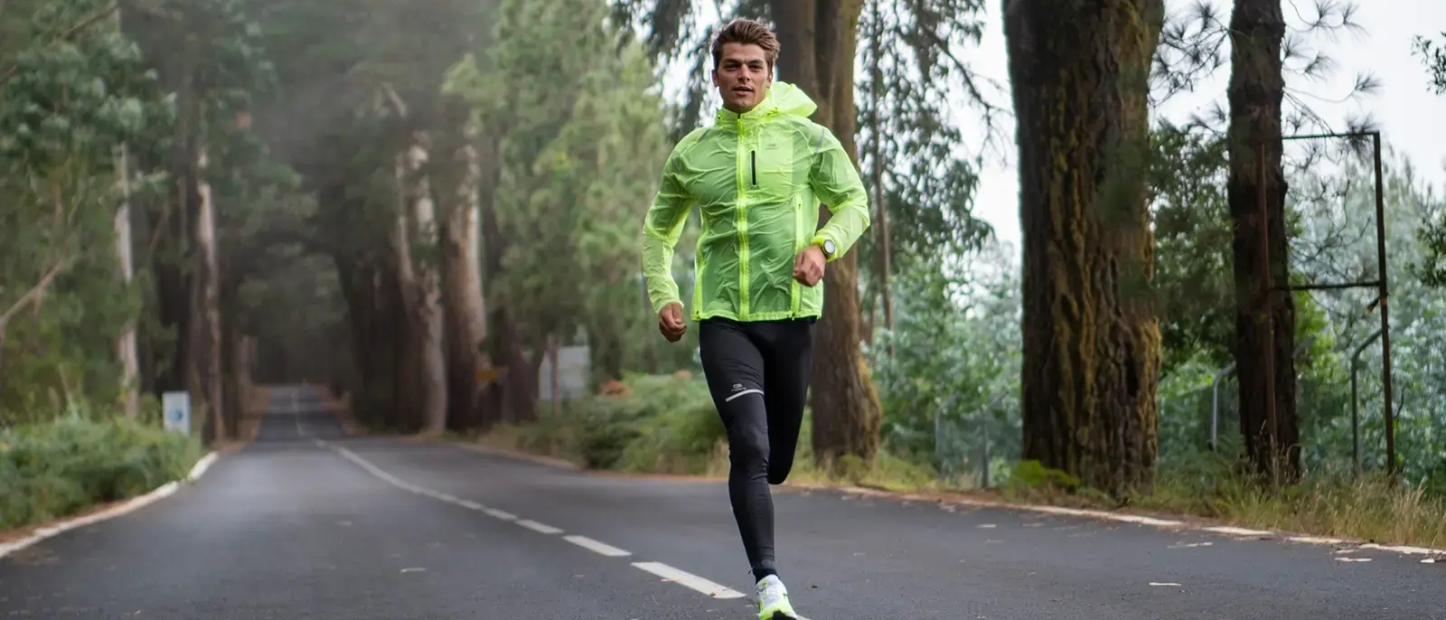 Man running in the middle of the road, in the woods.