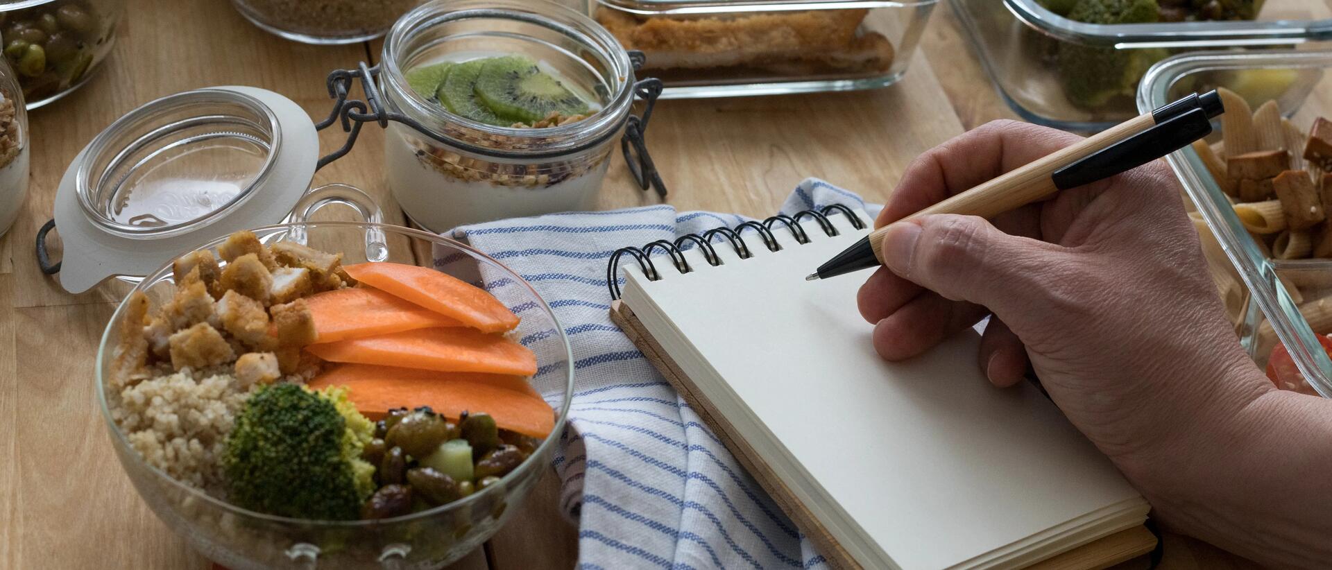 Man making notes on notepad with healthy food surrounding him