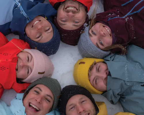 kobiety i mężczyźni leżący na śniegu w czapkach typu beanie