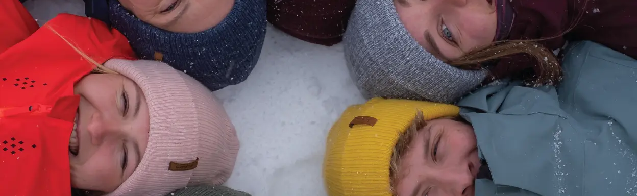 kobiety i mężczyźni leżący na śniegu w czapkach typu beanie