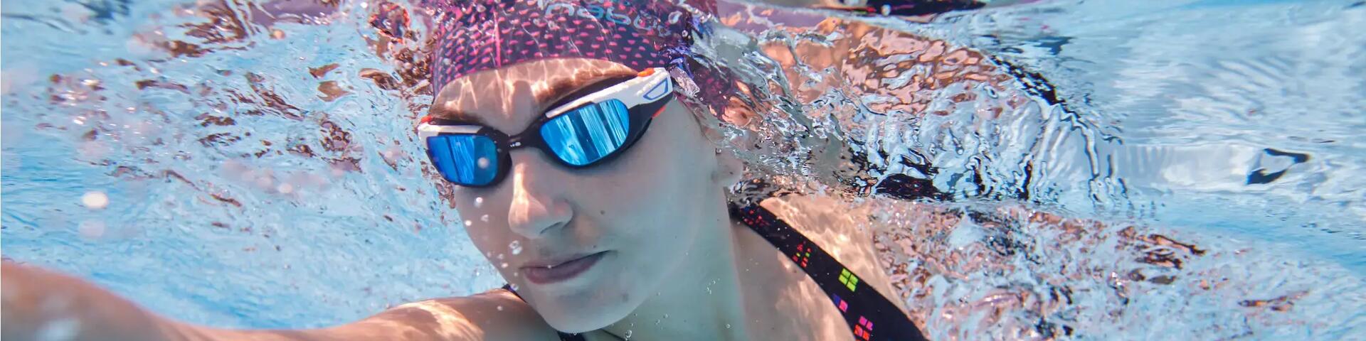 kobieta płynąca w czepku i okularach pływackich pod wodą