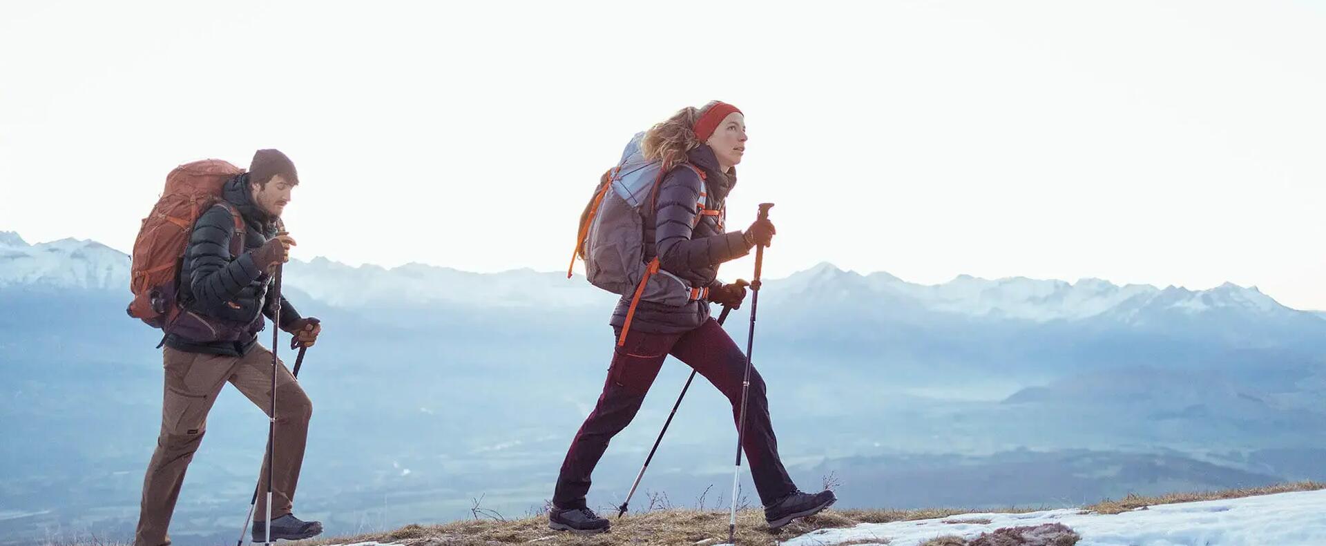 kobieta i mężczyzna w odzieży trekkingowej z kijkami w rękach wędrują po górach