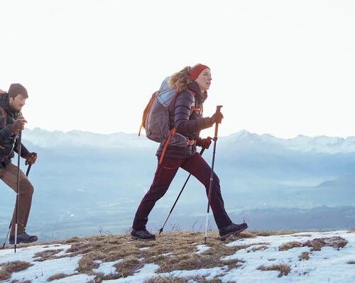 kobieta i mężczyzna w odzieży trekkingowej z kijkami w rękach wędrują po górach