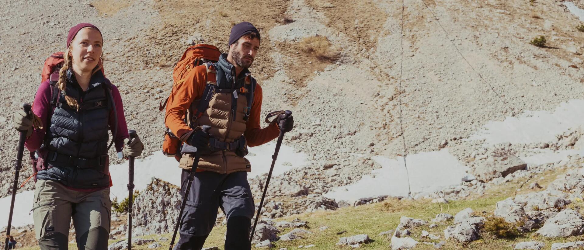 mężczyzna i kobieta idący w górach z kijkami  trekkingowymi