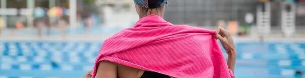 kobieta w czepku i kostiumie pływackim wycierająca się w ręcznik kąpielowy