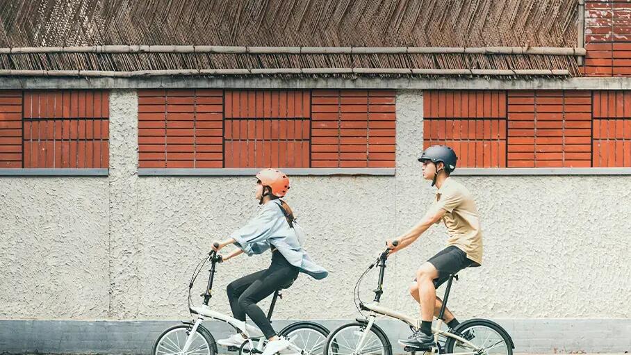 chłopak i dziewczyna jadący na rowerach miejskich w kaskach
