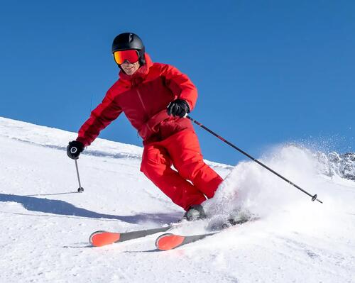 mężczyzna w kasku i goglach narciarskich zjeżdżający na nartach