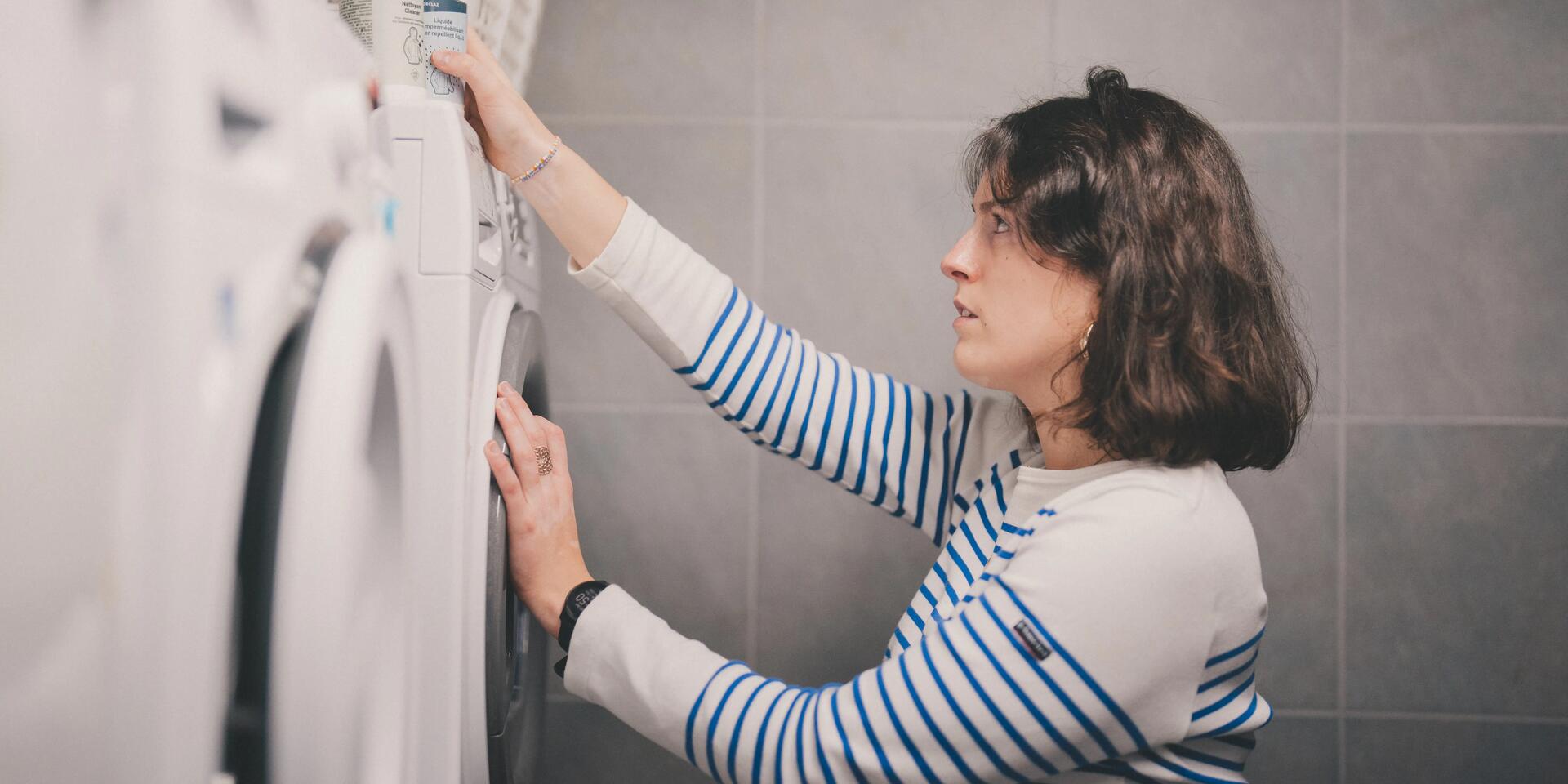 kobieta trzymająca preparat do prania stojący na pralce 