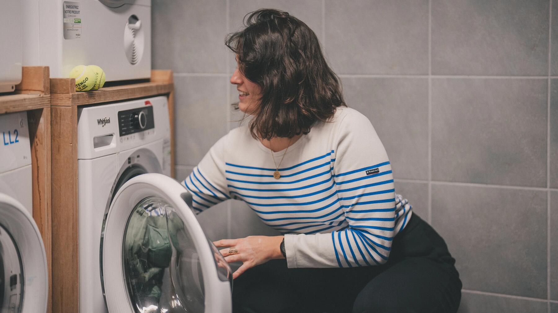 Kobieta ucząca się jak prać bieliznę termoaktywną wkładając odzież do pralki