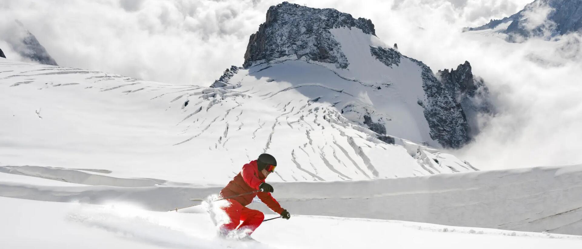mężczyzna w kasku i goglach narciarskich zjeżdżający ze stoku