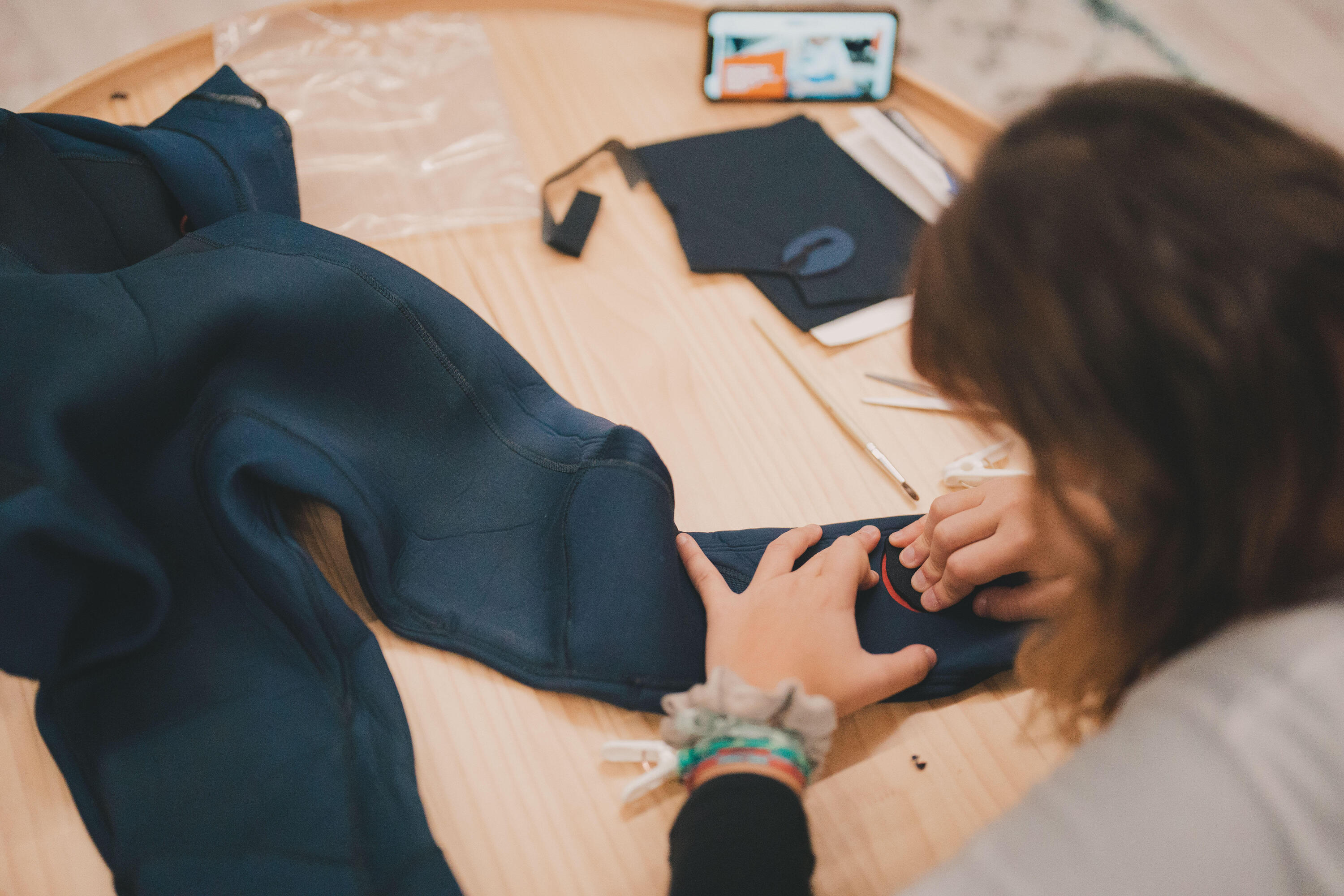 Frau repariert Loch im Hosenbein des Neoprenanzuges