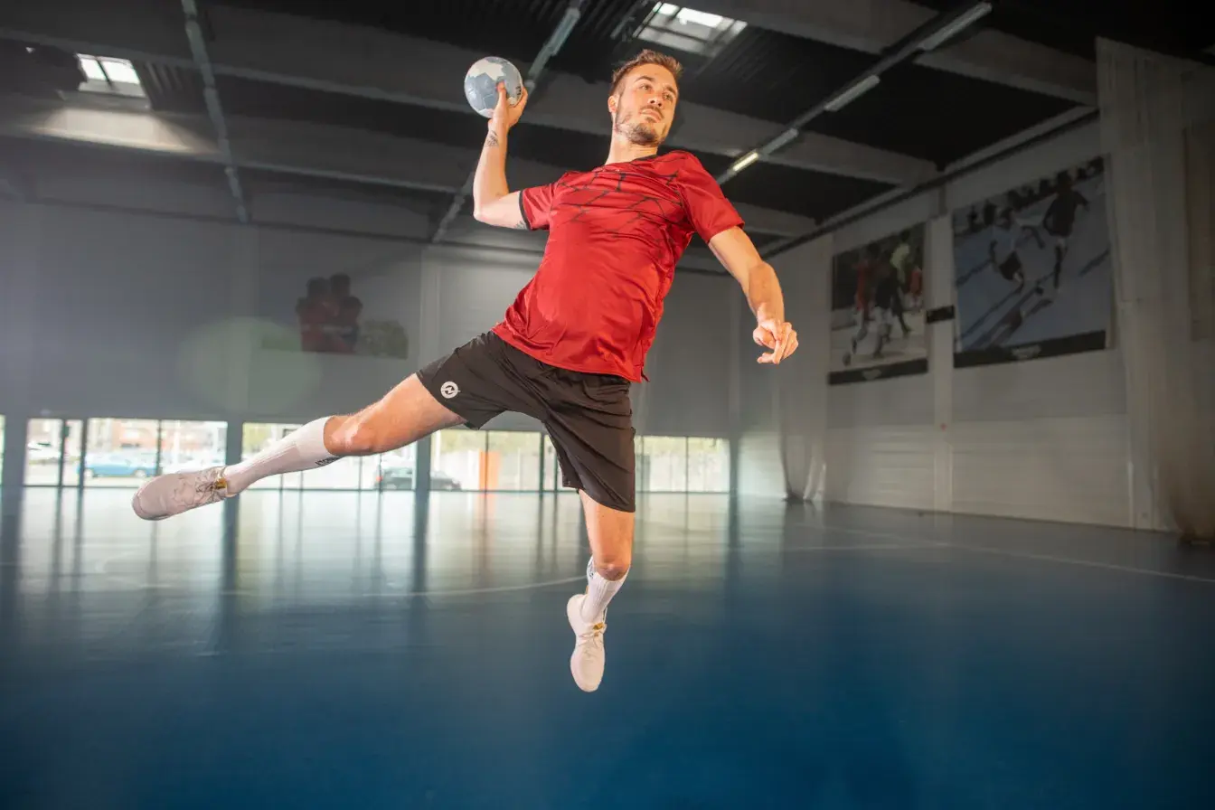 Mężczyzna w odzieży sportowej trenujący rzuty piłką do piłki ręcznej podczas treningu na hali
