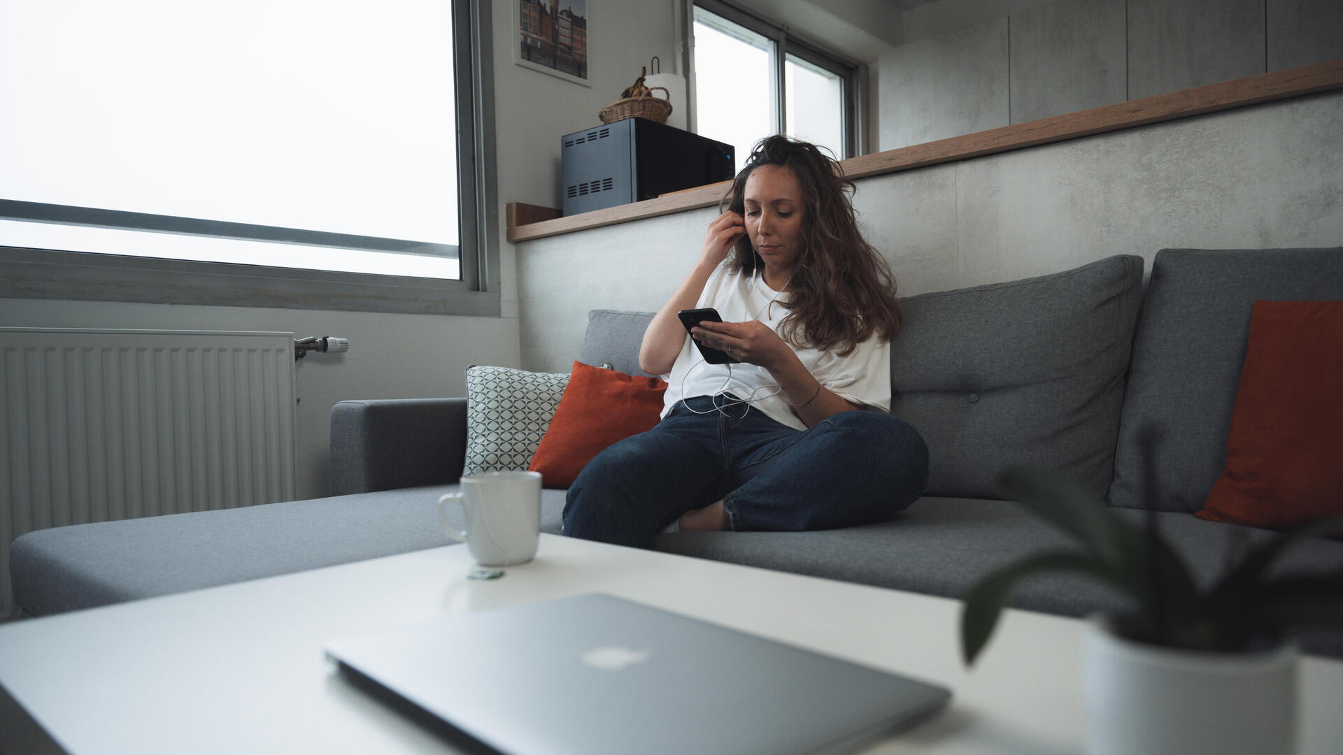 Femme consultant son smartphone, assise dans un canapé