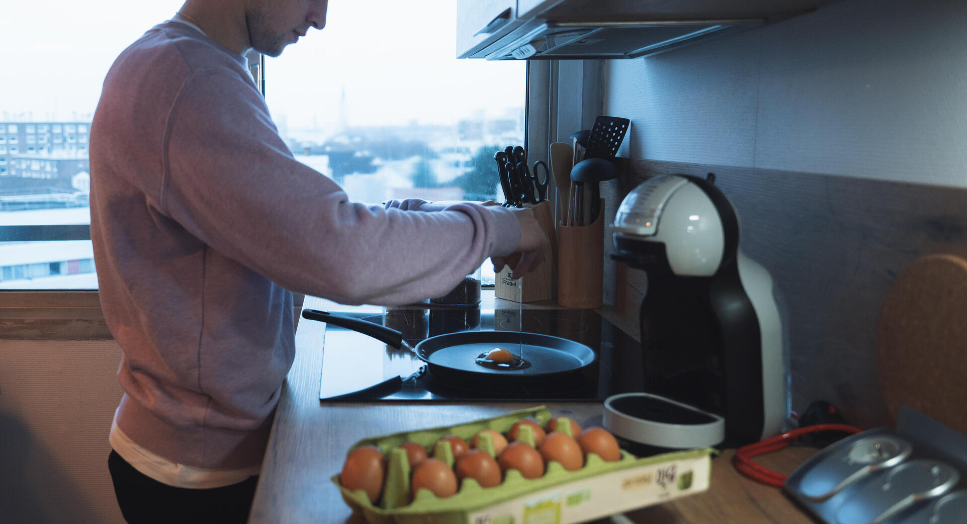 Jeune homme cuisinant des oeufs
