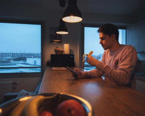 Homme qui mange une banane et consulte son smartphone