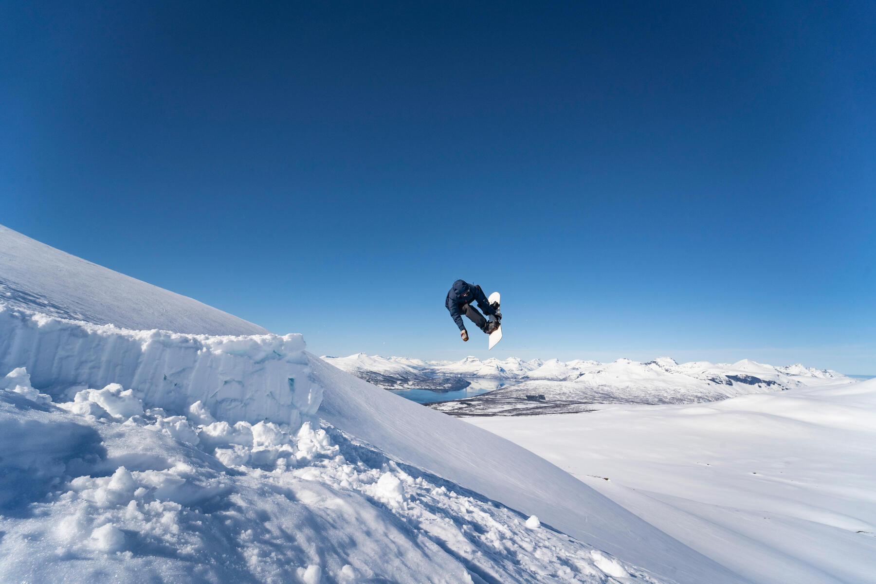 Snowboardzista z ubezpieczeniem wykonujący skok na desce snowboardowej
