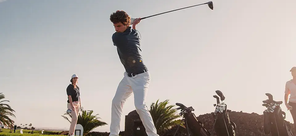 mężczyzna w butach do gry w golfa trzymający kij golfowy