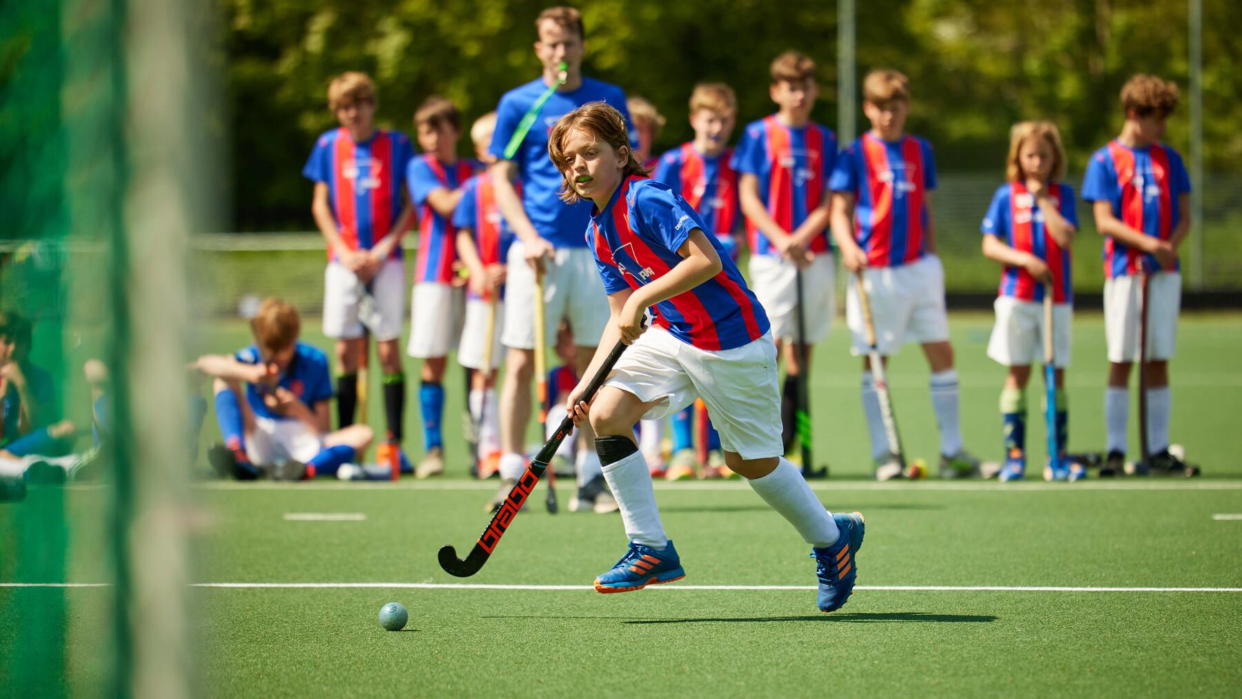 Een jonge hockeyspeler loopt naar het doel in de aanval, klaar om een doelpoging te doen