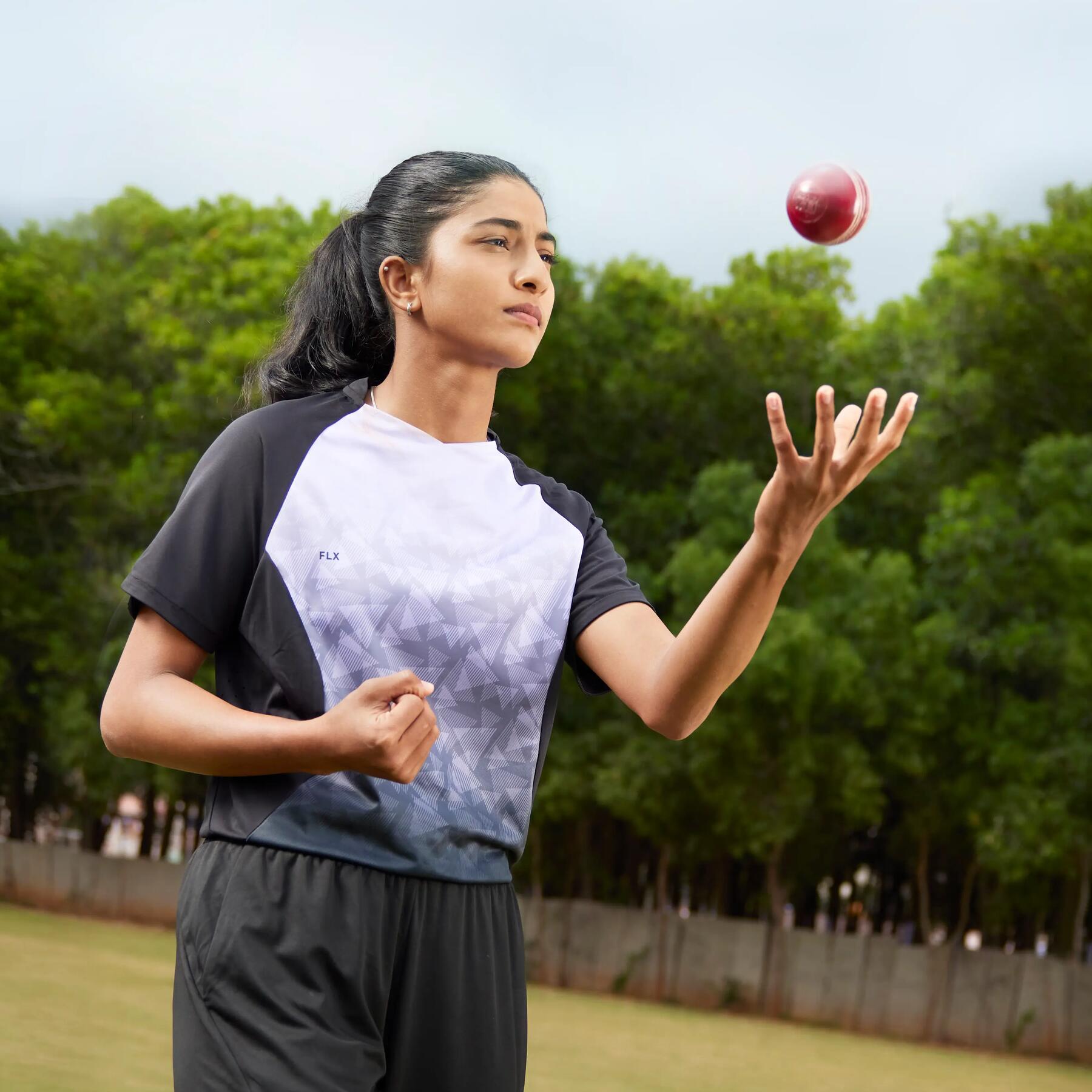Girl throwing cricket ball up in the air