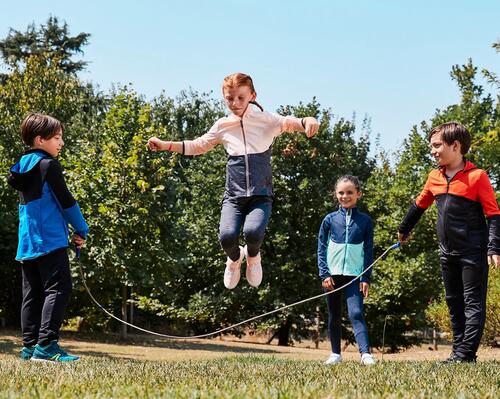 Dzieci w butach do chodzenia po szkole bawiący się w skakanie przez skakankę